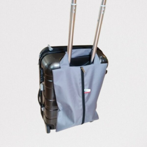 Sac à chaussures gris positionné sur la poignée pliable d'une valise