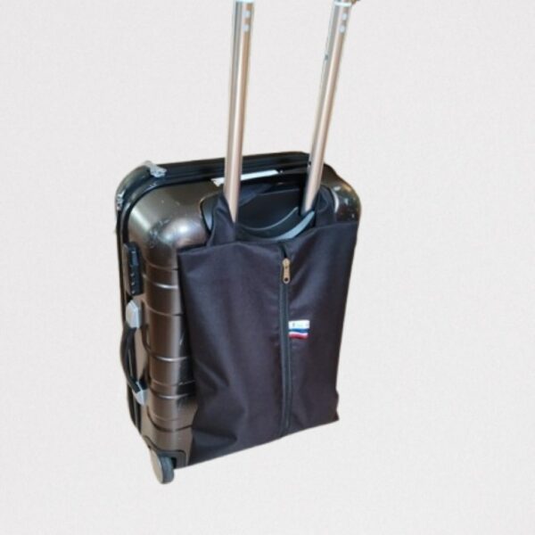 Sac à chaussures noir positionné sur la poignée pliable d'une valise