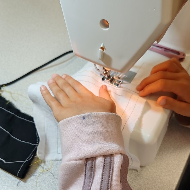 Main d'enfant en train de coudre sur une machine